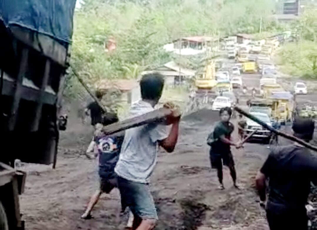 Beberapa sopir truk dan seorang warga mengacungkan kayu balok