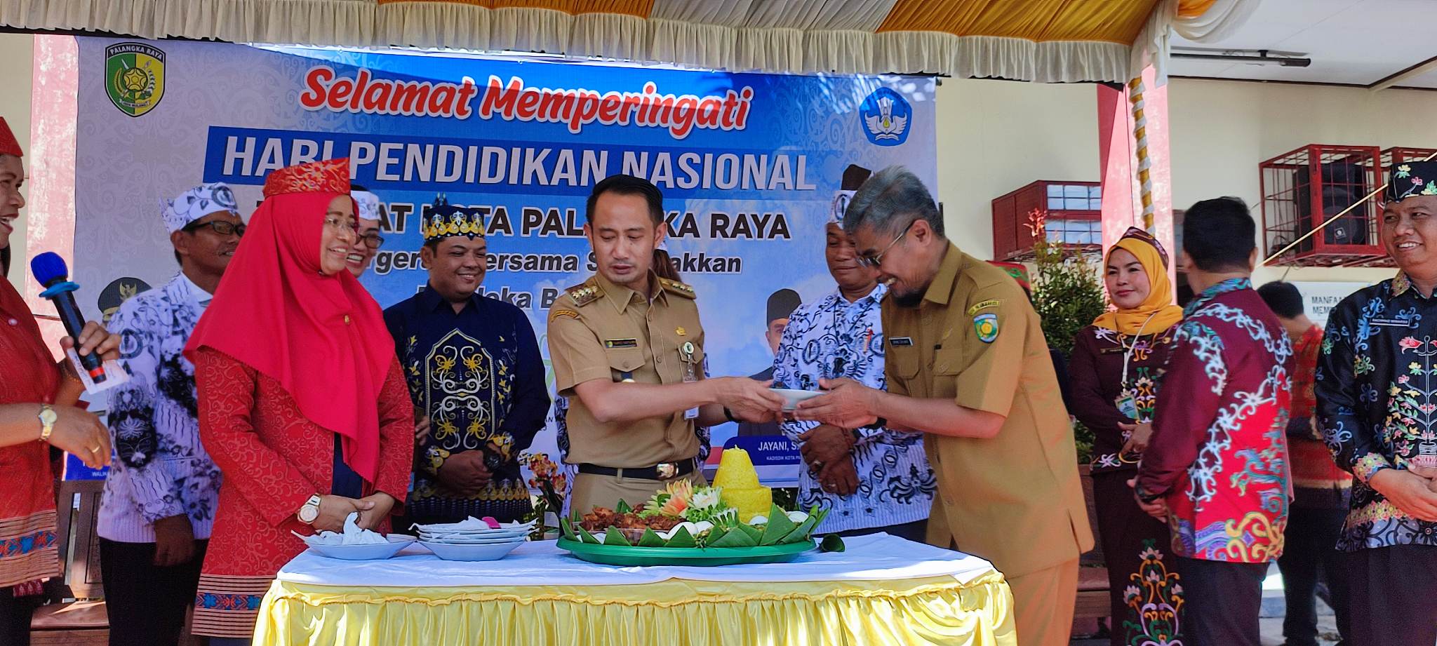 Wali Kota Palangka Raya Fairid Naparin saat memberikan potongan nasi tumpeng kepada Kadis Pendidikan Kota Jayani, saat memperingati Hardiknas 2023 di SMPN-1 Palangka Raya, Selasa (2/5).(dodi/radarsampit)