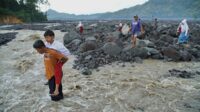 siswa sekolah dasar (sd) melintasi daerah aliran sungai (das) kali regoyo untuk berangkat sekolah di desa jugosari, kecamatan candipuro, lumajang, jawa timur